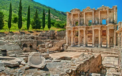 Antike Ruinen einer Bibliothek mit 3 verbliebenen Stockwerken, umgeben von Bäumen.