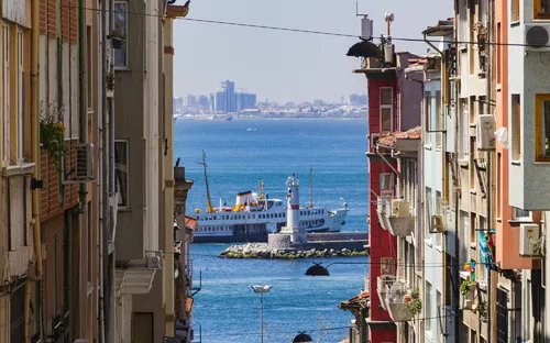 Blick zwischen Gebäuden auf ein Schiff auf dem Wasser bei sonnigem Wetter.