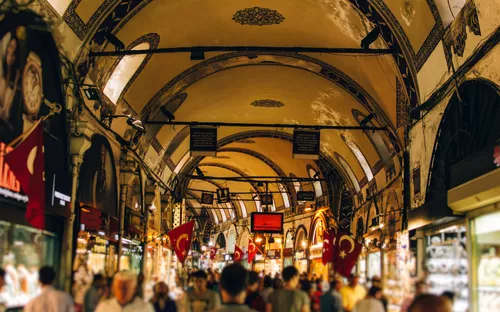 Menschenmenge in einem Basar mit Gewölbedecke und türkischen Fahnen.