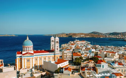 Stadt mit bunten Gebäuden und einer Kirche am Meer unter blauem Himmel.