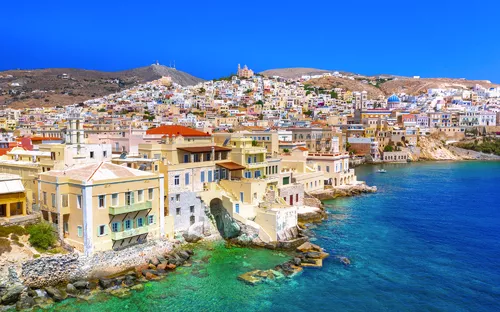 Küstenstadt mit pastellfarbenen Gebäuden und klarem blauem Meer.