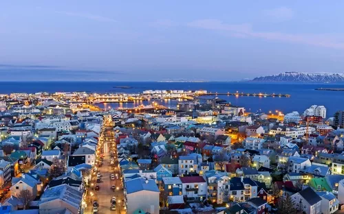 Luftaufnahme einer Stadt mit bunten Häusern und Hafen bei Dämmerung.