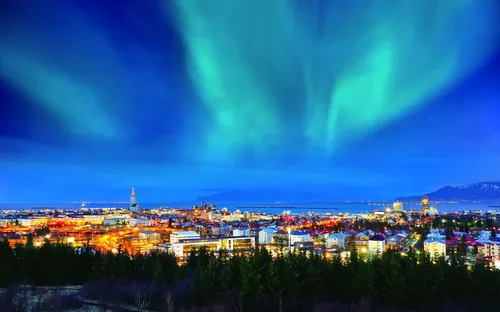 Polarlichter über einer beleuchteten Stadt bei Nacht.