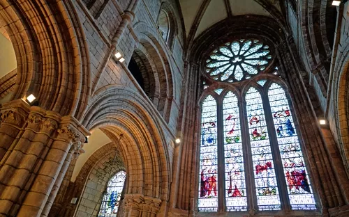 Gotische Kirchenfenster und Bögen aus Stein im Innenraum einer Kathedrale.