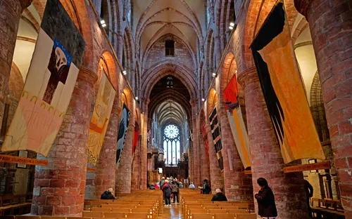 Innenansicht einer Kirche mit hohen Gewölben und hängenden Bannern.