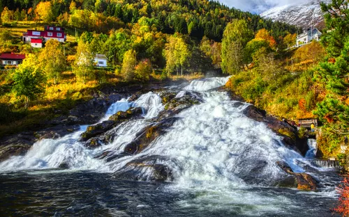 Wasserfälle in Hellesylt im Herbst, umgeben von buntem Laub und kleinen Häusern.