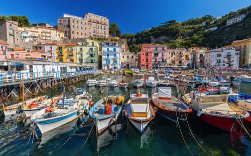 Fischerboote im malerischen Hafen vor bunten Häusern und Hügeln.