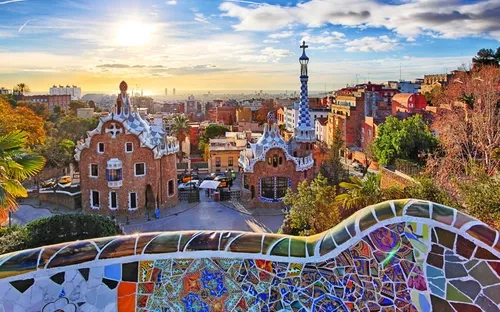 Park Güell in Barcelona mit buntem Mosaik im Vordergrund bei Sonnenuntergang.