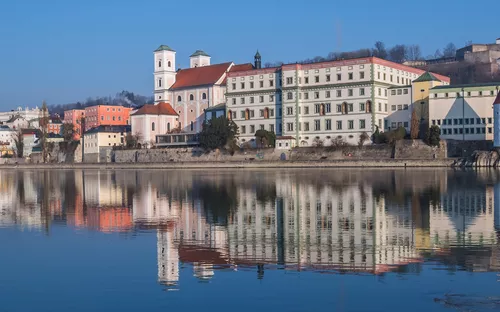 Historische Stadtansicht mit Flussreflexionen bei klarem Himmel.