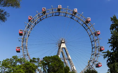 Riesenrad in einem Park mit blauem Himmel im Hintergrund.
