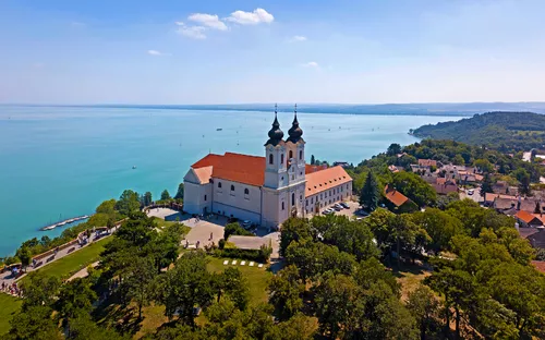 Basilika auf einem Hügel mit Blick auf einen großen blauen See und umliegende grüne Landschaft.