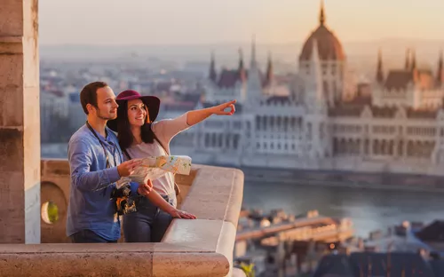Paar mit Karte blickt auf Stadt im Sonnenuntergang, Gebäude im Hintergrund.