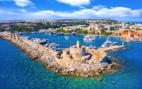 Blick auf den Hafen von Rhodos mit Yachten und mittelalterlichem Turm.