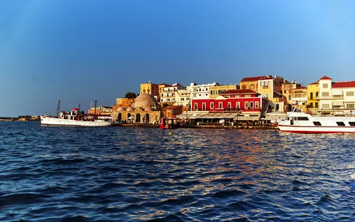 Hafen mit Booten und farbigen Gebäuden am Wasser bei Sonnenuntergang.