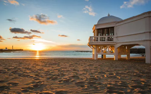 Strand von Cádiz in Andalusien, Spanien, bei Sonnenuntergang mit berühmtem Pier im Vordergrund.