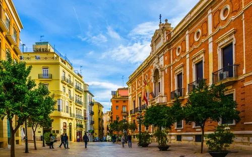 Städtische Straße mit historischen Gebäuden und Menschen, die spazieren gehen.