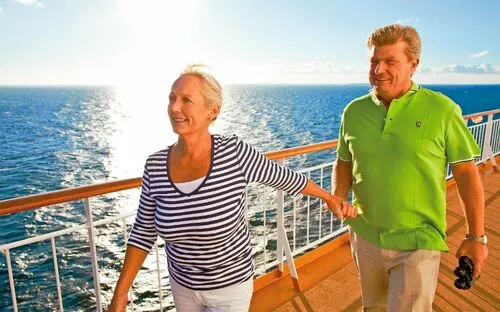 Personen spazieren an Deck eines Kreuzfahrtschiffs bei sonnigem Wetter.