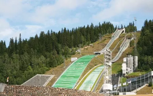 Skisprungschanze im Olympiapark Lillehammer umgeben von Wald.