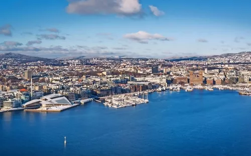 Stadtansicht von Oslo mit Hafen im Vordergrund bei klarem Himmel.