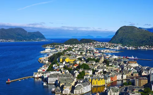 Küstenstadt mit bunten Gebäuden und Bergen am Meer.