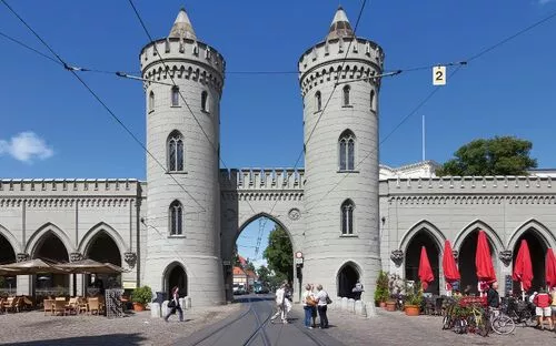 Historische Toranlage mit zwei runden Türmen und Menschen auf der Straße.