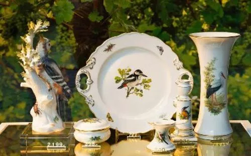 Porzellangeschirr mit Vogelmotiven, ausgestellt vor Weinranken.