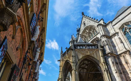 Gotische Kirche und historisches Backsteingebäude unter blauem Himmel