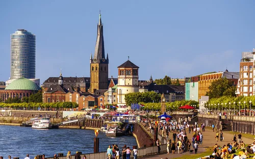 Panorama der Düsseldorfer Altstadt mit Rheinufer und Menschen.