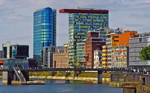 Moderne Gebäude am Rheinufer mit Brücke im Vordergrund.