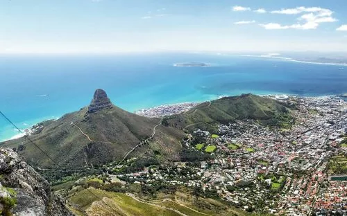 Blick vom Berg auf Küstenstadt und Meer unter klarem, blauem Himmel.