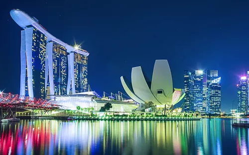 Singapore Skyline bei Nacht mit beleuchteten Gebäuden am Marina Bay.