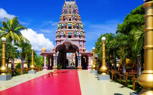 Hindutempel auf Mauritius mit buntem Eingangstor und Palmen im Hintergrund.