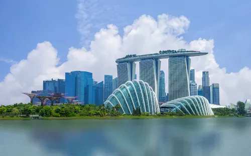 Skyline von Singapur mit Marina Bay Sands und Gardens by the Bay vor blauem Himmel.