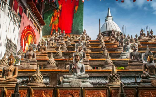 Reihe von Buddhastatuen vor einem Tempel unter blauem Himmel