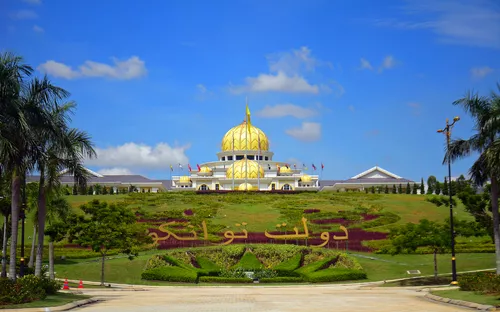 Palast in Malaysia mit goldener Kuppel und Gartenanlage.