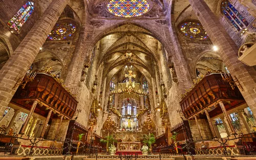 Innenansicht einer prächtigen gotischen Kathedrale mit bunten Glasfenstern.