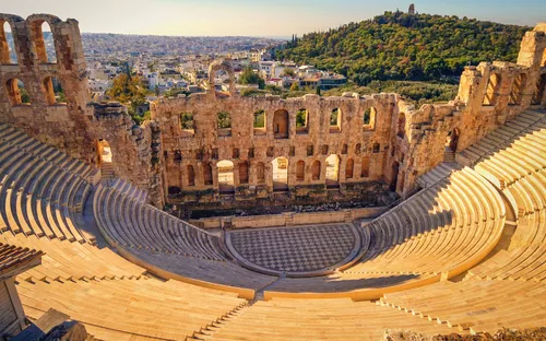 Antikes Amphitheater mit Steinbögen und Blick auf eine Stadt bei Sonnenschein.