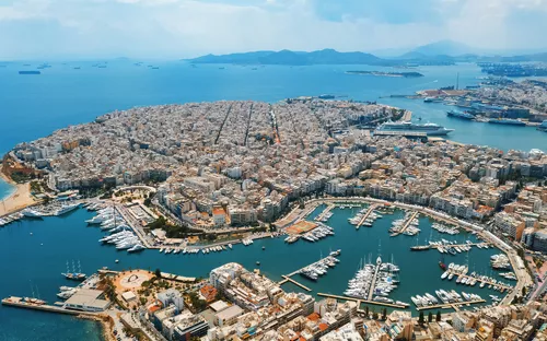 Luftaufnahme eines großen Jachthafens und einer dicht bebauten Stadt am Meer.