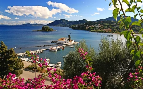 Küstenlandschaft mit Kloster auf der Insel, umgeben von Meer und Blumen im Vordergrund.