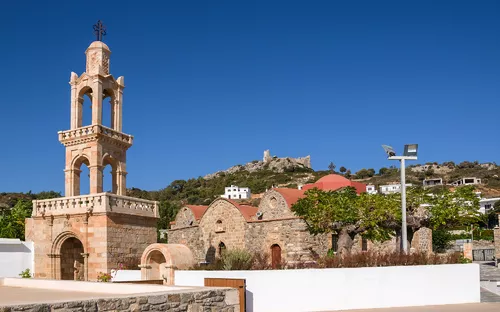 Historische Kirche mit Glockenturm vor blauem Himmel.