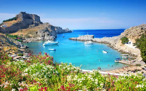 Malerische Bucht mit blauem Wasser, Segelbooten und grünen Hügeln im Hintergrund.