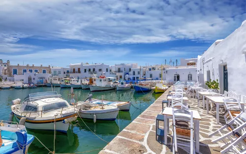 Boote in einem malerischen Hafen mit weißgetünchten Gebäuden und blauen Himmel.