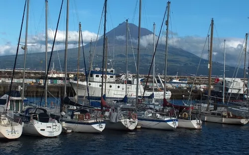 Segelboote im Hafen vor einem bergigen Hintergrund.