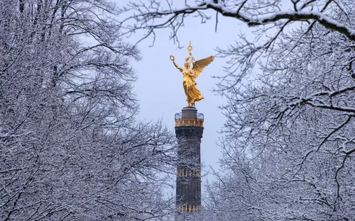 Siegessäule in Berlin, umgeben von schneebedeckten Bäumen im Winter.