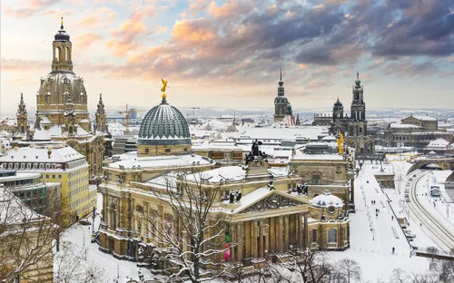 Verschneite Stadtansicht mit historischen Gebäuden bei Sonnenuntergang.