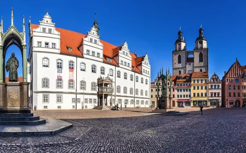 Marktplatz mit historischem Rathaus und Kirche an einem sonnigen Tag.