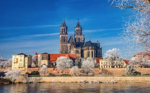 Kathedrale hinter verschneiten Bäumen an einem Fluss.