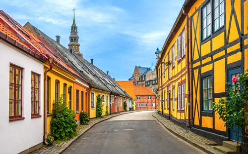 Farbige Fachwerkhäuser in einer engen, gepflasterten Altstadtstraße.