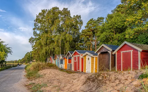 Strandhütten in Ystad, Schweden, umgeben von Bäumen und einem sandigen Weg.