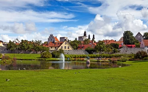 Historische Altstadt mit Teich und Wiese im Vordergrund, Wolken am Himmel.